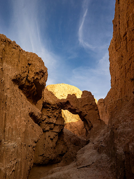 Hiking in a cayon carved from mud, an arch awaits at the trail's end.