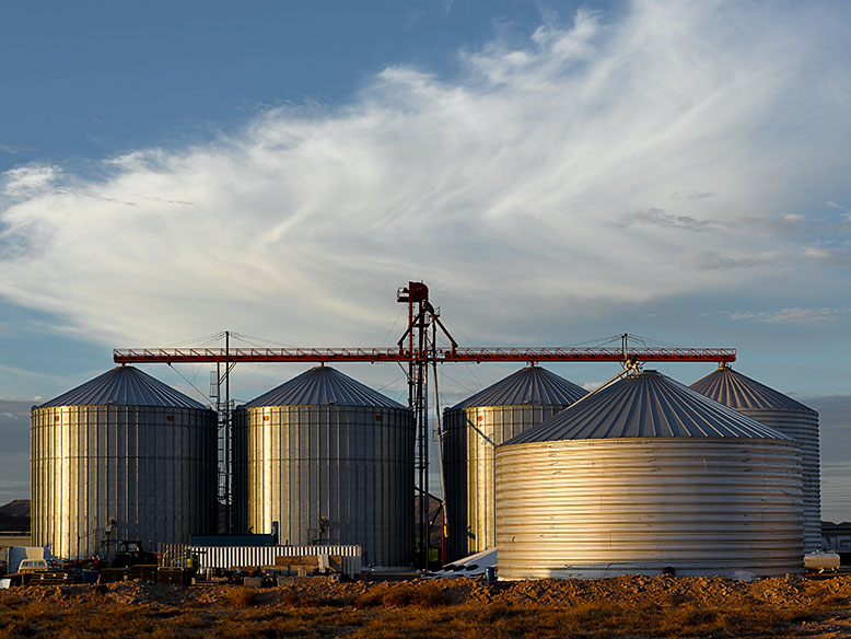 Daybreak lights up the clouds over grain silos in Goodyear, Arizona. Photo by Jim Witkowski.