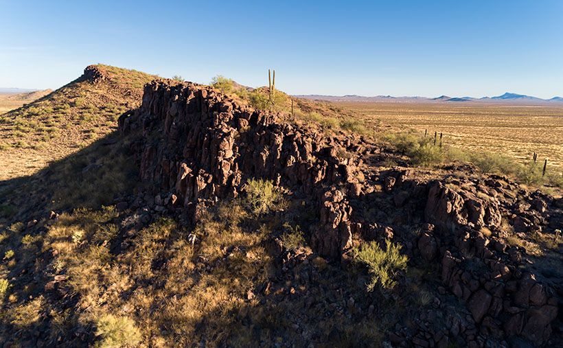 Stunning hill formations in the Harcuvar Mountains, sculpted by plate tectonics, with a double-headed saguaro in the foreground.