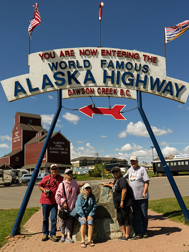 Gang under ALCAN Highway sign,