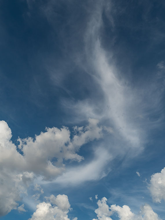 Cirrus Streak - A wispy streak of cirrus clouds thousands of feet above monsoon cumulus clouds forming above the mountain tops.