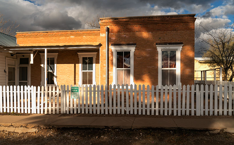 White Pickets and Red Bricks - A break in the cloudy sky let sun light the face of a Tombstone Apartment.