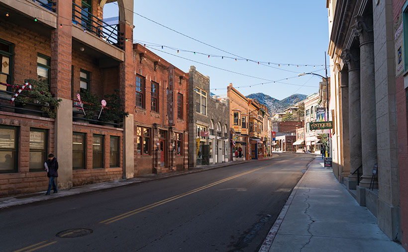 A view of Bisbee's Main Street, with its colorful storefronts, snow-capped mountains, and decorative lights.
