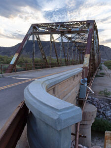 Rustic Gillespie Bridge spanning the Gila River with a mountain in the background