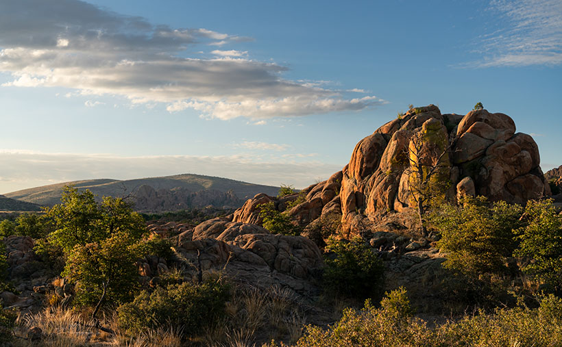 Golden morning light illuminating the rugged landscape of Granite Dells, with Glassford Summit in the background.