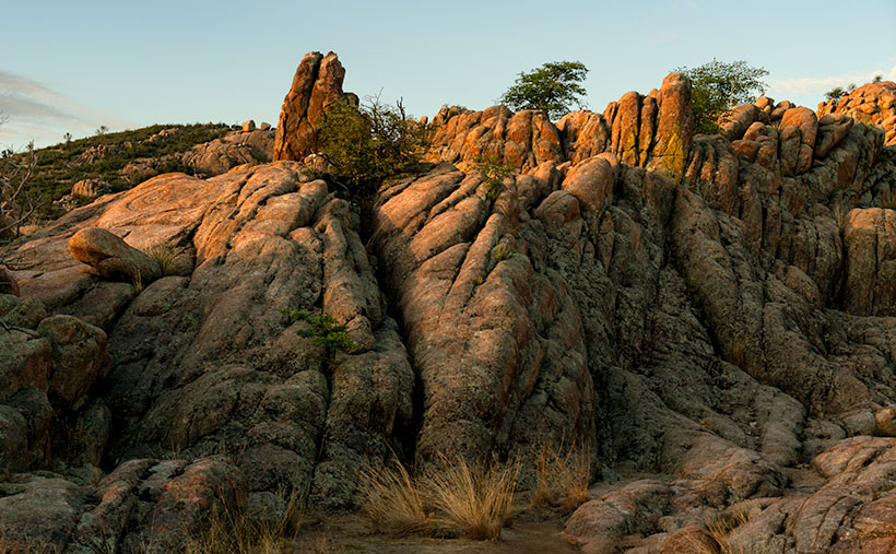 A subtle sunrise over the Granite Dells in Prescott, Arizona, highlighting lichen-covered rocks resembling toes and victory signs.
