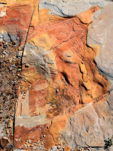 Water or ice erosion exposing red sandstone layers beneath the surface in Whitney Pocket, Gold Butte area.