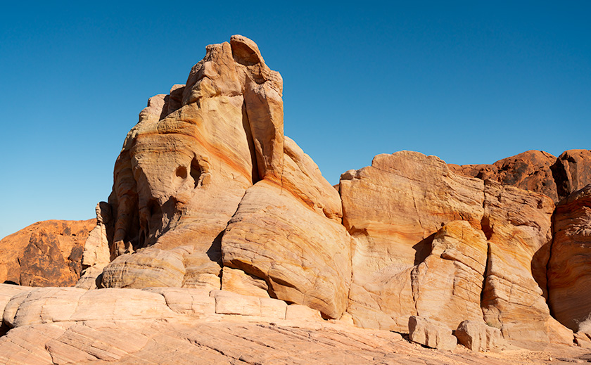 A towering formation of layered Navajo sandstone, named 'whiteGibraltar', stands under a clear blue sky in Valley of Fire State Park, Nevada.