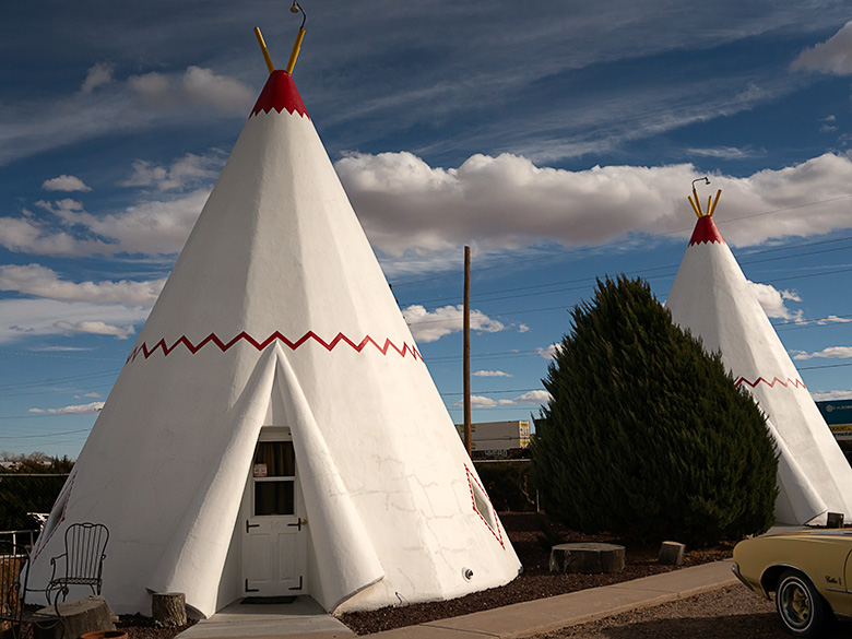 White tee pee-shaped motel rooms with classic car parked outside on Route 66 in Holbrook, Arizona