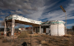 Faded green signage on an abandoned gas station under dramatic sky in Holbrook, Arizona