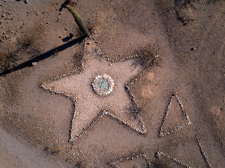 Drone photo of a five-point star made of stones with a blue-glass center, surrounded by desert terrain near Sundad, Arizona