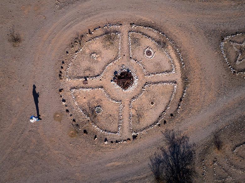Drone photo of large rock circle in Sundad, Arizona with four quadrants, a rusted center, and the photographer’s shadow on the left