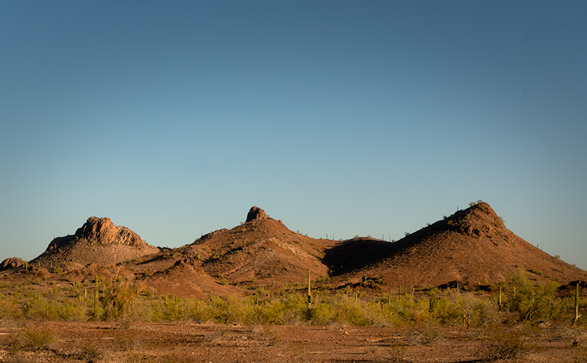 Three desert peaks surrounded by cacti and brush, photographed in Arizona near Signal Mountain Wilderness.