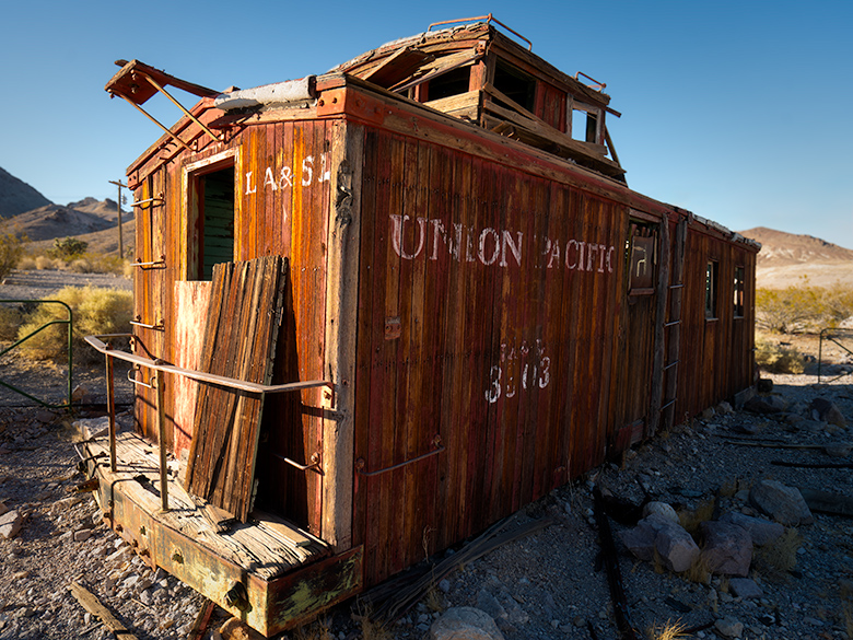 Abandoned Union Pacific caboose outside Rhyolite hotel in Nevada ghost town Weathered caboose car parked outside the historic Rhyolite hotel in Nevada