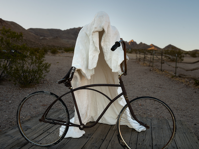 White ghostly sculpture with bicycle, The Ghost Rider by Albert Szukalski, at Goldwell Open Air Museum near Rhyolite train station