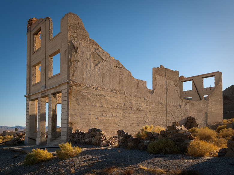 Cook Bank building in Rhyolite, Nevada bathed in sunset light. Ruins of the historic Cook Bank building in Rhyolite, Nevada illuminated by the last rays of sunlight