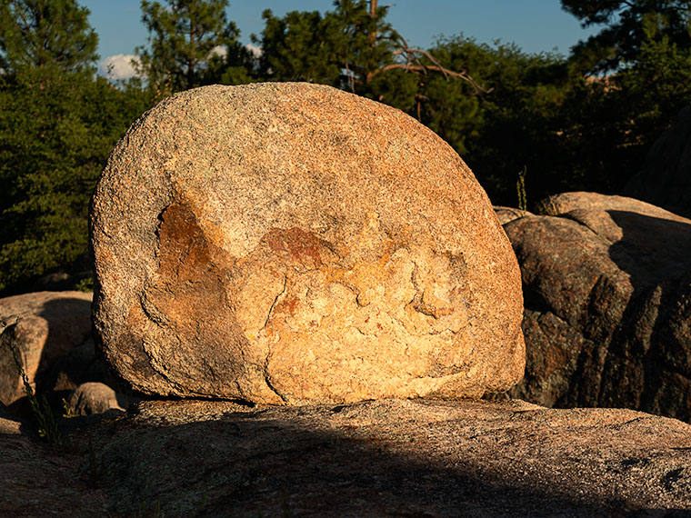 A singular rock, bathed in golden light, resembling a deflated beach ball or Yosemite's Half Dome, in the Granite Dells.