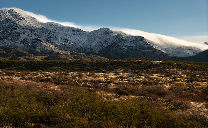 Snow blankets the rugged peaks around Yarnell, contrasting the warm desert terrain of Congress, Arizona.