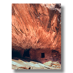 Anasazi-era ruin built into a sandstone wall with fiery patterns on Cedar Mesa, Utah.