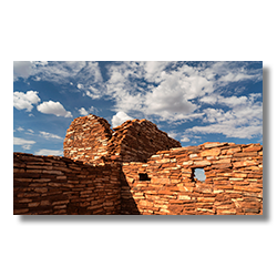 The Lomaki ruins at Wupatki National Monument, resembling cinder cone formations against a backdrop of dynamic clouds.