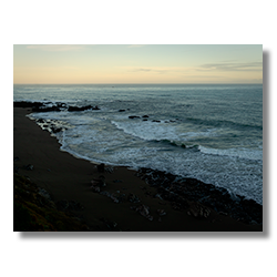 Early morning view looking south over Moonstone Beach in Cambria, California, with waves breaking gently on a rocky shoreline