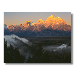 Early morning ground fog tumbles into the Snake River Gorge as the sun comes up on the Grand Tetons.